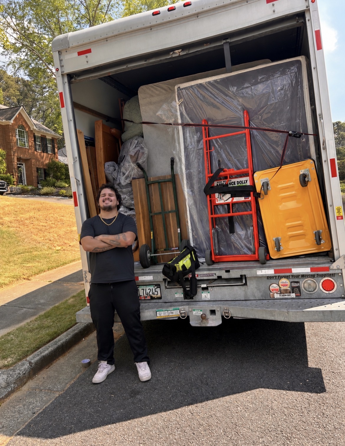 Team member beside an open moving truck loaded with wrapped furniture and dollies