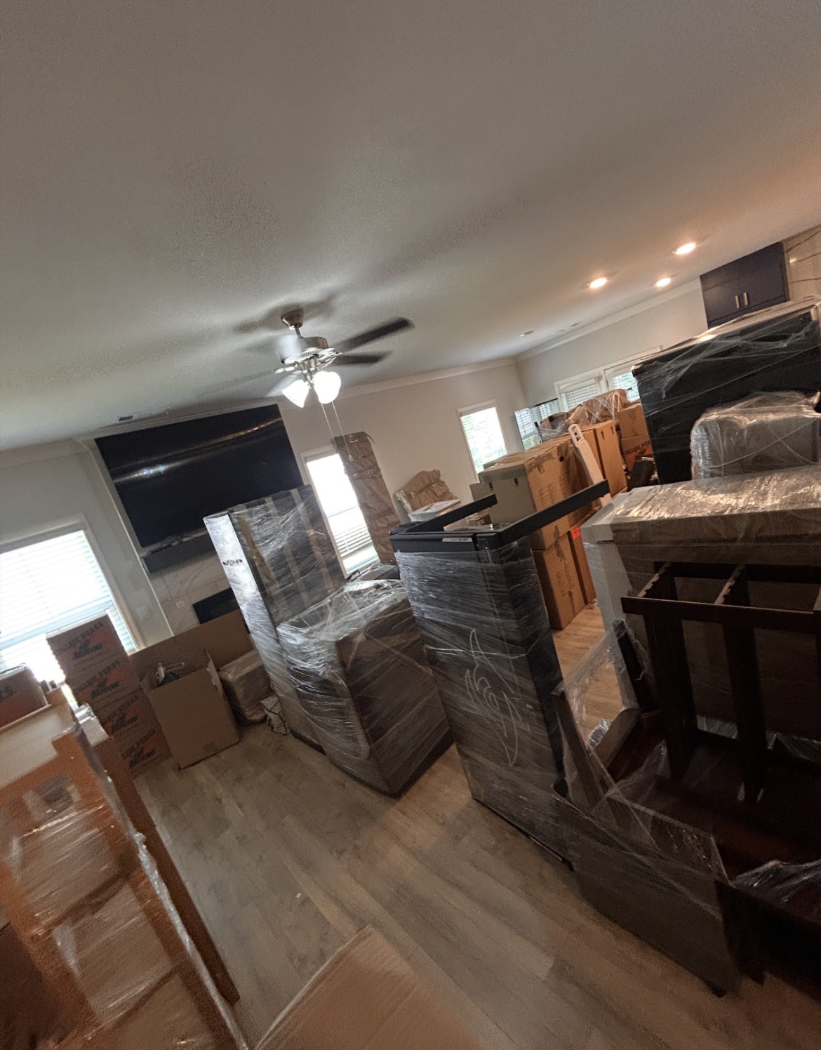 Furniture wrapped in protective film and moving boxes inside a home